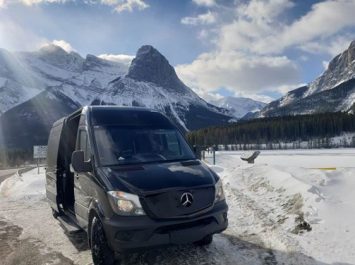Mercedes Mini Party Bus parked in front of snow and mountains in Banff Alberta