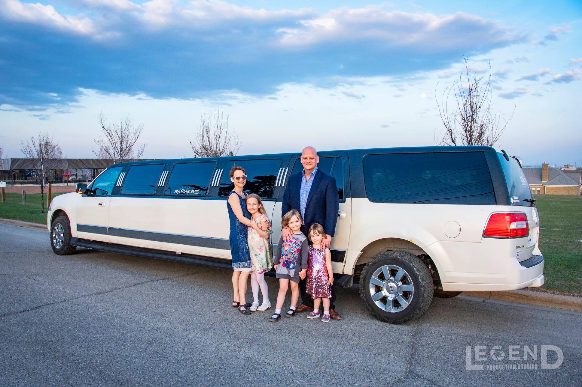 Family with 2 adults and 3 children standing in front of the white and black Lincoln Navigator Stretch Limousine
