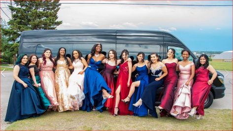 13 girls in dresses celebrating Graduation with black mini party bus