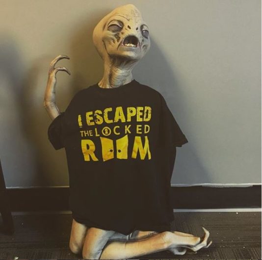 photo of an alien prop wearing an "I escaped the Locked Room" t-shirt